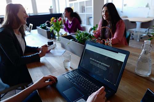 human two woman smiling while sitting in front of table person