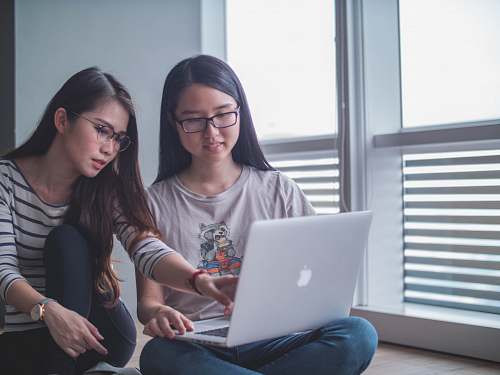 electronics two women discussing each other while looking on laptop computer