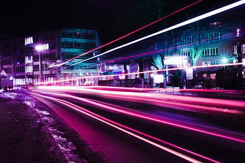 neon timelapse photography of pink vehicle lights near buildings purple