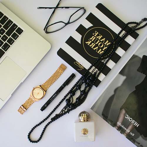 australia clear eyeglasses with black frames; beaded black necklaces; black pen; round gold-colored analog watch with link bracelet in flat lay photography flat lay