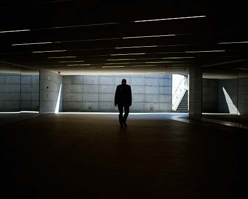 grey silhouette photo of person walking inside dark room piazza gae aulenti
