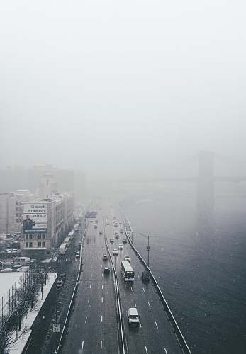 grey aerial view of vehicle on road beside body of water fog