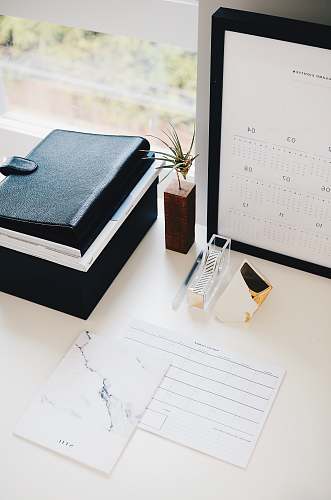 desk books and calendar on white table plant