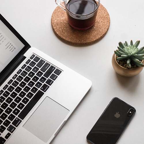 computer space gray iPhone X beside turned on laptop beside coffee and succulent plant mobile phone