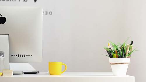 jar yellow ceramic mug beside gray aluminum iMac plant