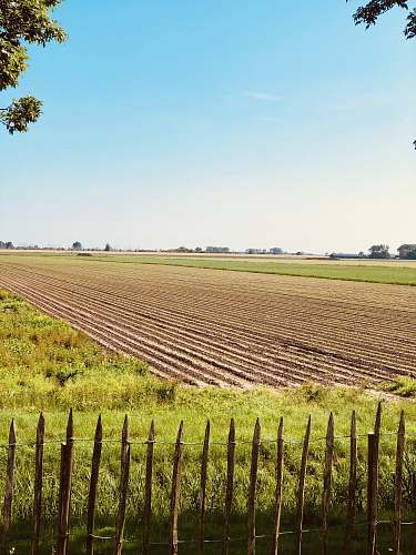 nature plowed soil between grass field land