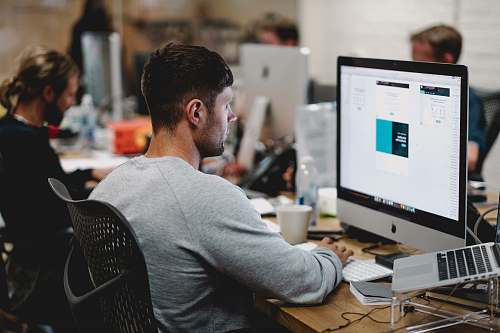 person man in gray sweatshirt sitting on chair in front of iMac human