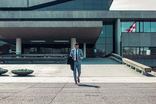 human man walking while holding black coat suit