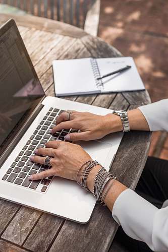 laptop person typing on MacBook Pro on brown wooden table during daytime photo work