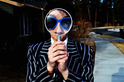 person person using magnifying glass enlarging the appearance of his nose and sunglasses magnifying glass