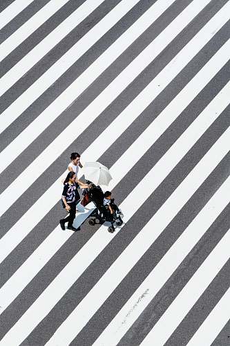 tarmac two women and baby crossing striped floor road