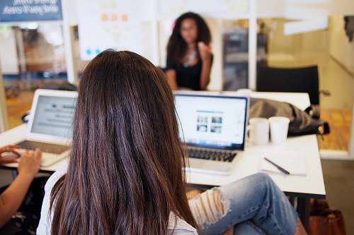 person woman sitting while looking at turned on laptop on tabletop human