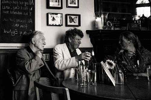 people grayscale photo of three man sitting beside table human