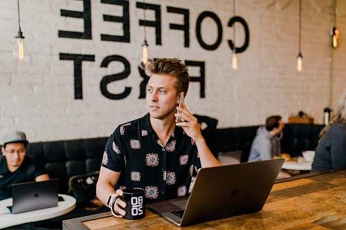 human man holding phone white using MacBook electronics