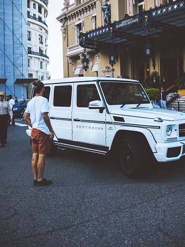 human man standing beside white SUV during daytime car