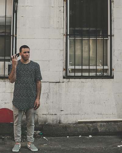 human man standing in front of building while holding phone during daytime people