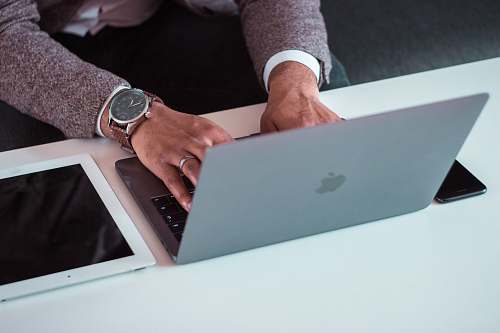 electronics man using MacBook between iPad and iPhone wristwatch