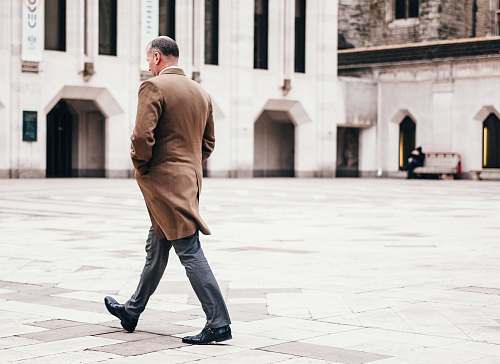 human man walking in front of white building people