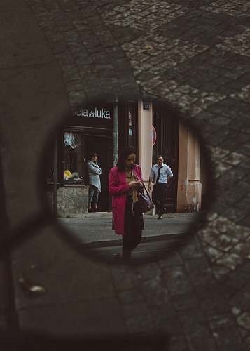 human mirror showing woman wearing pink coat walking on street people