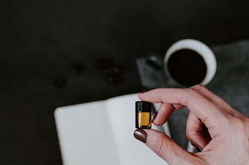 human person holding small oil bottle finger