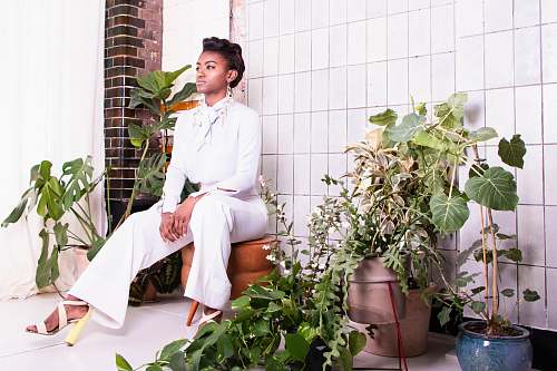 apparel sitting woman wearing withe long-sleeved shirt and pants surrounded by plants clothing