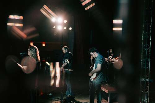 human three men playing on stage lighting