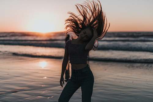 human woman flipping hair on seashore during sunset people
