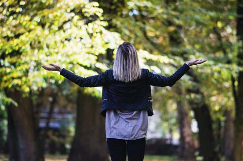 human woman in black long-sleeved top in front of green leafed tree people