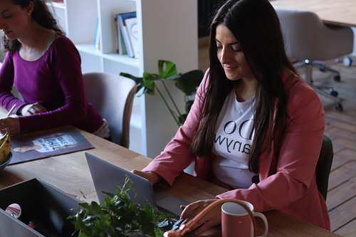 human woman sitting facing on laptop coffee cup