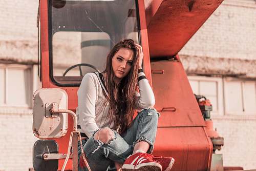 people woman sitting in front of red heavy equipment while resting her hand on head human