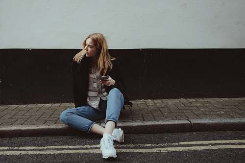 people woman sitting on floor while holding smartphone girl