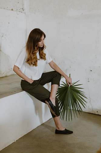 clothing woman sitting on white concrete surface apparel