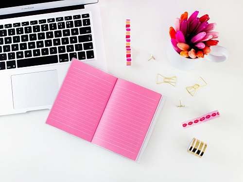 desk pink lined notebook beside MacBook Air blog