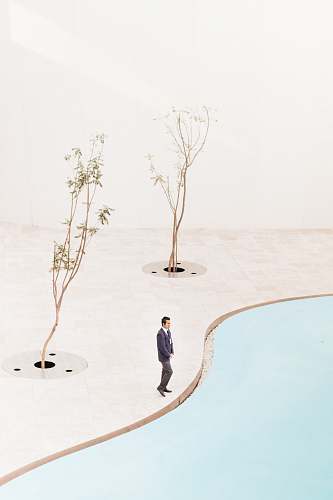 art man standing near two trees at daytime pool side