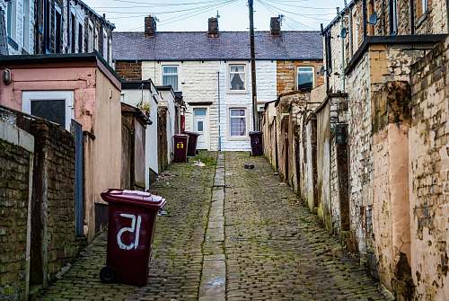 path trash bins near wall beside houses walkway