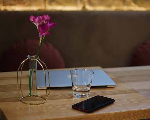furniture clear shot glass beside black smartphone wood