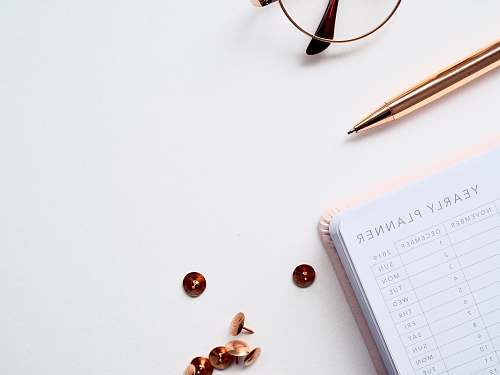 electronics buttons and thumbtacks beside planner book on table phone