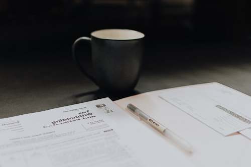 pen coffee mug near open folder with tax withholding paper diary