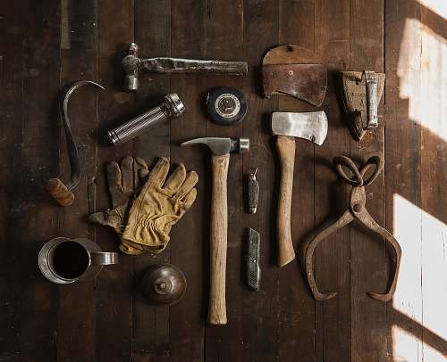gloves clothes iron, hammer, axe, flashlight and pitcher on brown wooden table tool