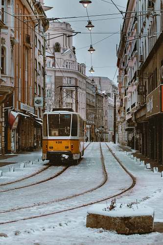 vehicle orange and gray train beside brown concrete building \ cable car