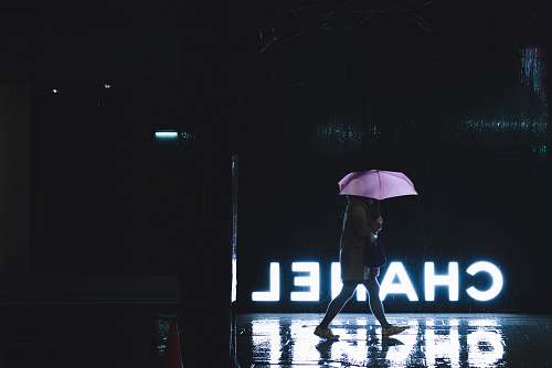 japan woman walking under umbrella passing by Chanel lighted signage canopy