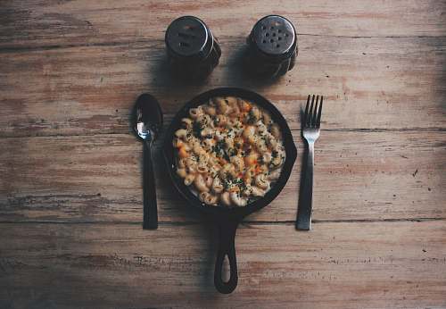  cooked food on black plate beside fork and spoon on brown wooden table 