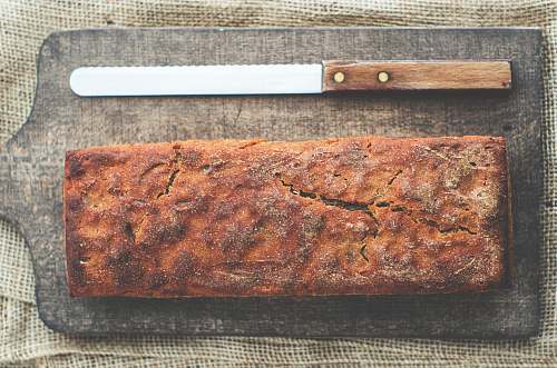 food bread and bread knife on top of brown wooden chopping board loaf