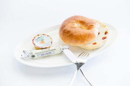food bread on white plate with fork and table knife bagel