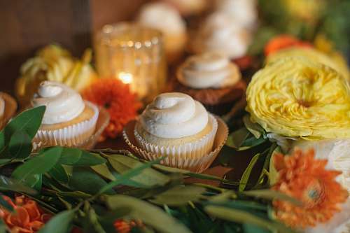 dessert baked cupcake beside yellow and orange flowers cake