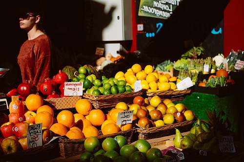 fruit assorted fruits on fruitstand beside woman in brown top citrus fruit