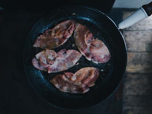 cooking bacon on top of black cast-iron skillet pan