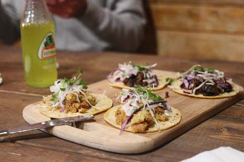 taco board of four soft tacos on table drink