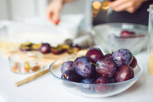 fruit bowl of red grapes on white tabletop plum