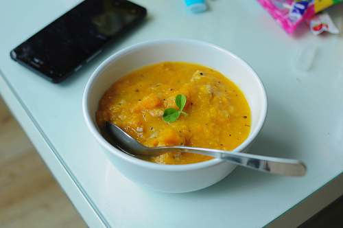 bowl bowl of soup with spoon beside smartphone dish